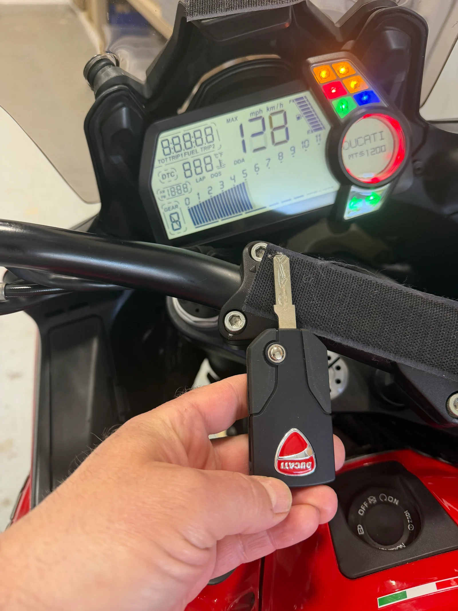 Freshly programmed Ducati Multistrada 1200 flip key held in front of the bike's MTS 1200 dashboard after a successful key replacement