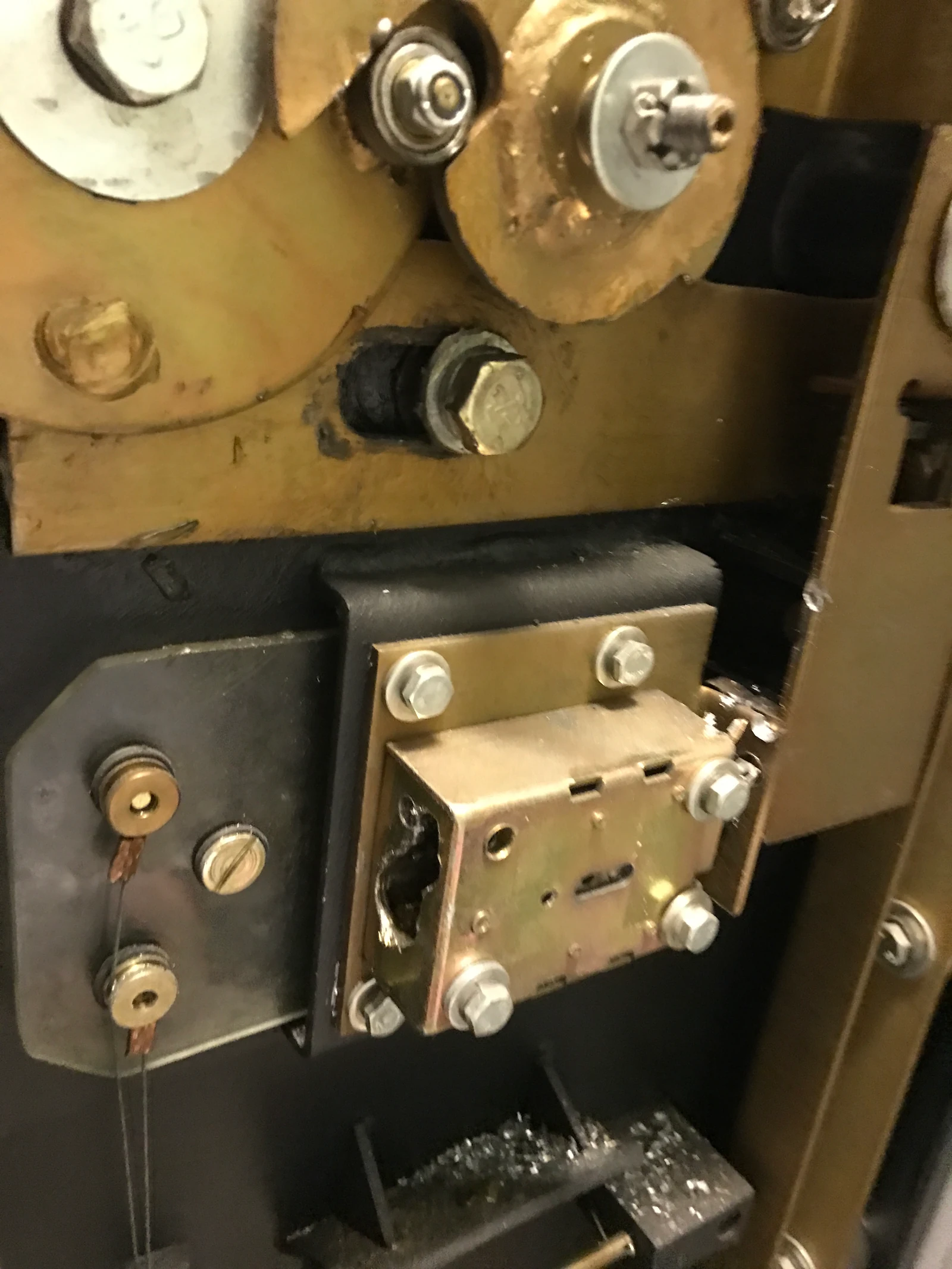 Inside view of a commercial safe after precision drilling — brass boltwork still intact, lock module exposed, drill shavings visible from the controlled-entry process